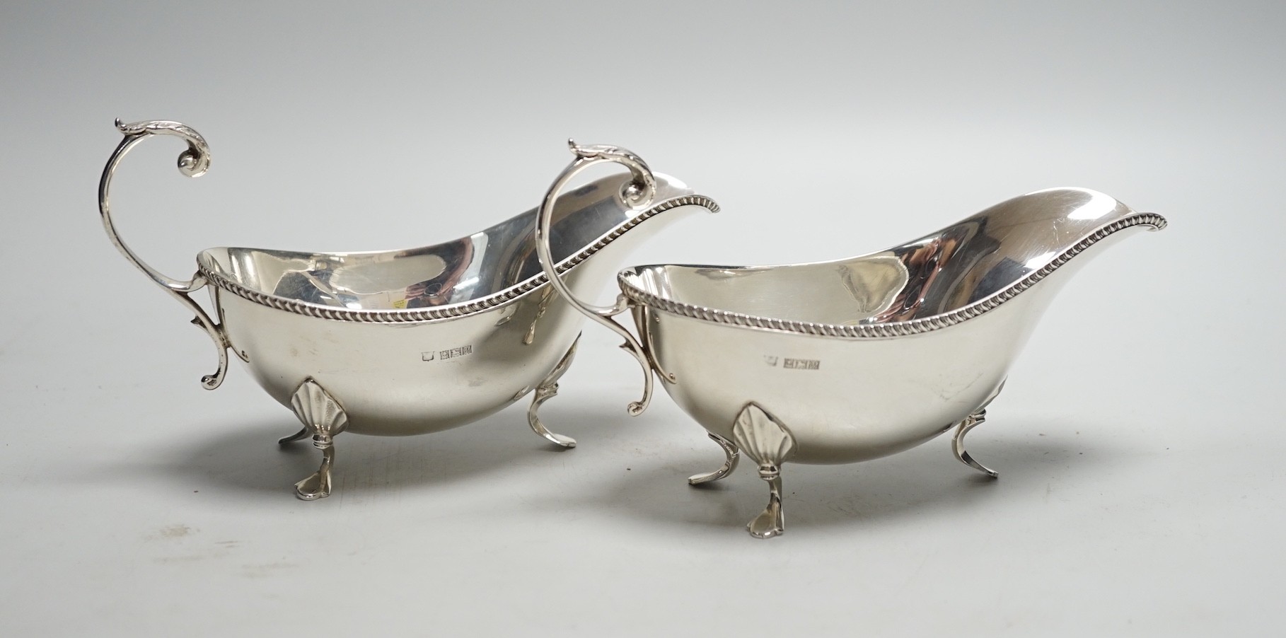 A pair of Elizabeth II silver sauce boats, with flying scroll handles, Poston Products Ltd, Birmingham, 1961, length 18cm, 11.3oz.